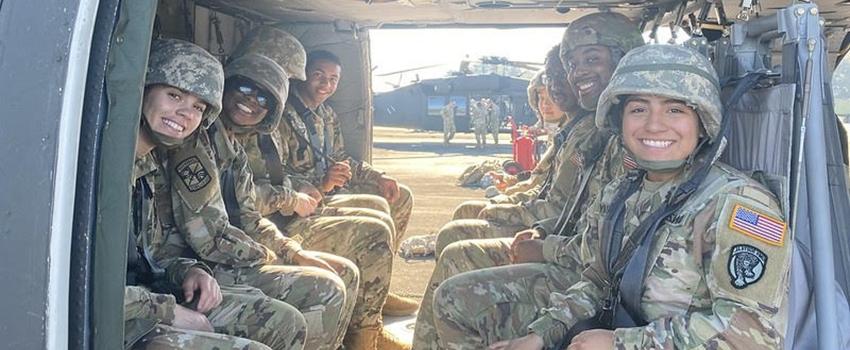 Eight Cadets onboard helicopter with additional helicopter and cadets in field in the background