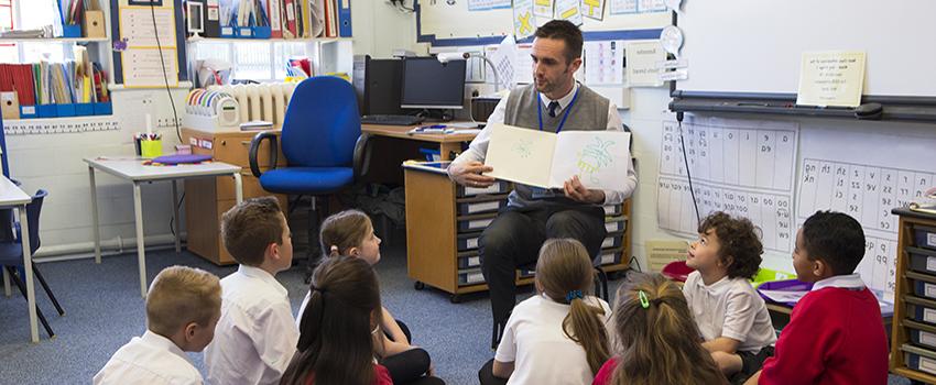 Male teacher reading book to class.